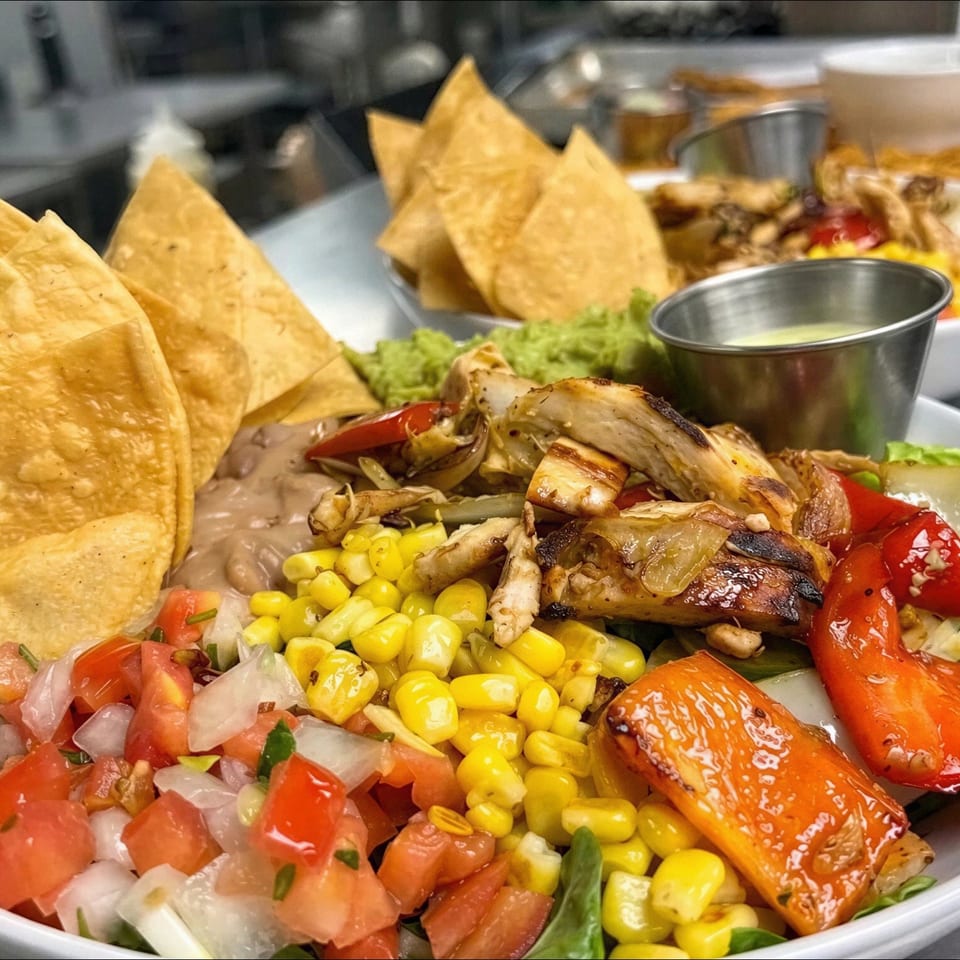 Loaded salad bowl with grilled chicken, corn, roasted peppers, pico de gallo, beans, greens, tortilla chips, and dressing.