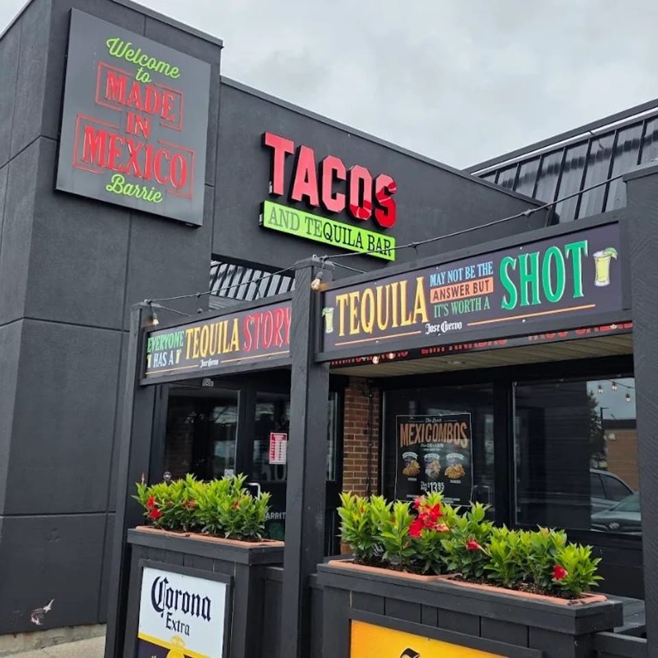 Exterior of a colorful Mexican restaurant and tequila bar with large taco signage, flower planters, and Corona branding.